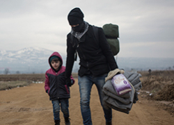 Un hombre y un niño refugiados caminando por una carretera de tierra