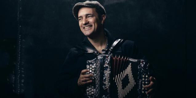 El artista retratado con una gorra mientras toca su acordeón diatónico
