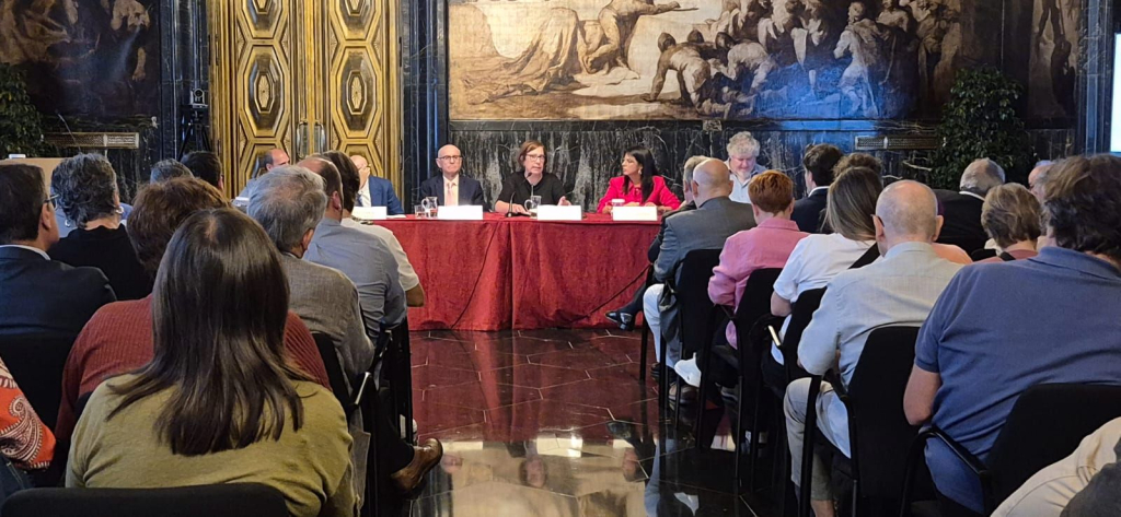 Vista del públic i la taula presidencial al fons. Intervenció de Raquel Gil, tinenta d'Alcaldia qui presideix l'acte. 