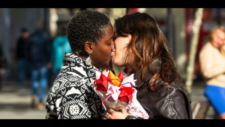 Una parella es fa un petó amb unes roses a les mans al passeig de Gràcia (Autor: Elena Pastor)