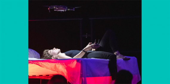Performance “Speculative Intimacy. Afectes i tecnologia digital”, dins la Biennal de Pensament del 2019. Moment de l'actuació amb una dona estirada al llit comandant un petit dron. © Xavier Torrent