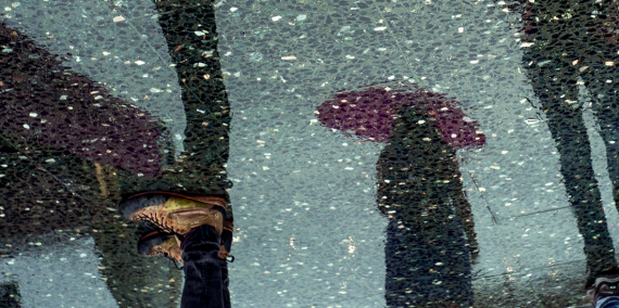 L'ombra de tres persones que duen paraigües reflectida sobre un terra de marbre. © Sergi Capellas