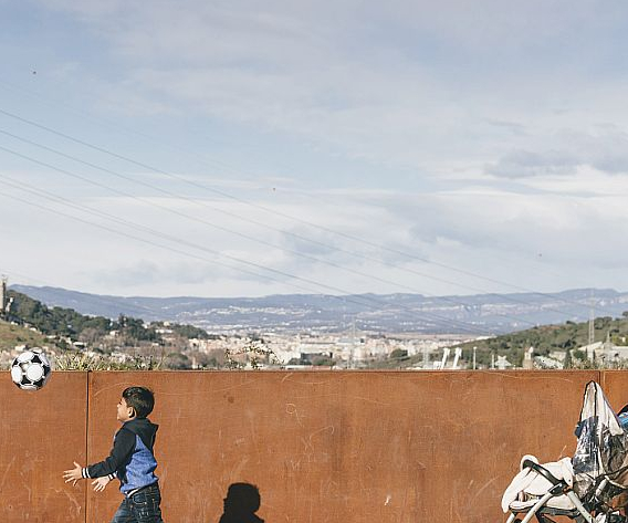 © Leo García. Barri de la Trinitat Nova: Un nen amb una pilota travessa el pont de la Meridiana i darrera es veu una dona amb un cotxet.
