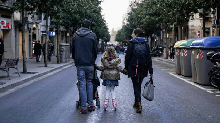 Família caminant plegada per un carrer de ciutat.