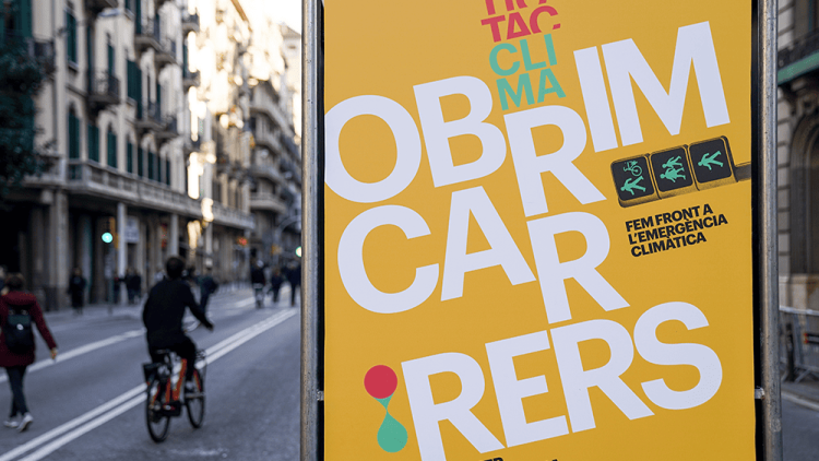 Cartell groc al carrer amb el missatge “Obrim carrers”