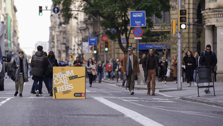 Vianants en un carrer tallat amb un cartell d’Obrim Carrers