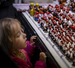 A little girl looks in awe at the caganers on display at a stall at the Sant Llúcia Fair