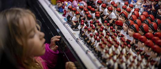 A little girl looks in awe at the caganers on display at a stall at the Sant Llúcia Fair