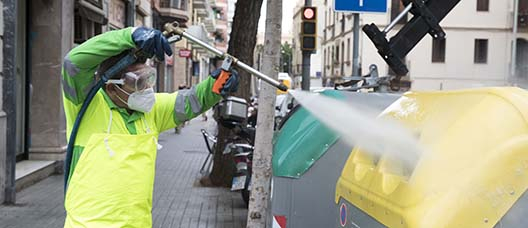 Un treballador del Servei de Neteja renta amb aigua a pressió uns contenidors situats a la plaça de Gal·la Placídia i entorns 