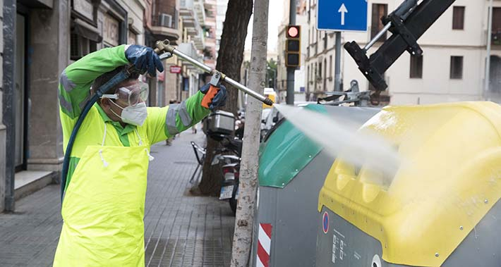 Un treballador del Servei de Neteja renta amb aigua a pressió uns contenidors situats a la plaça de Gal·la Placídia i entorns 