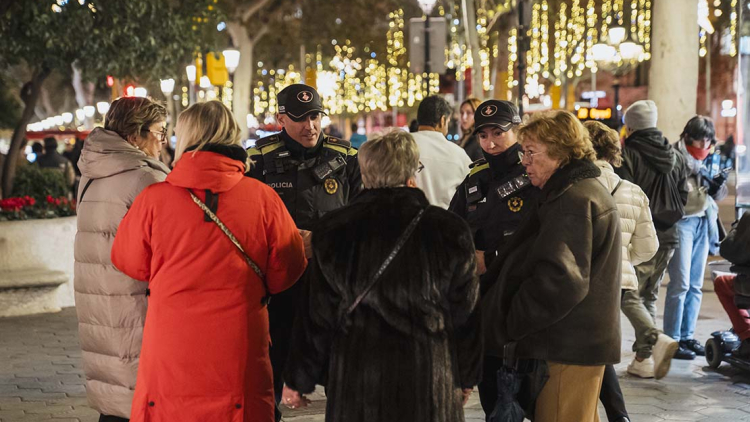 La Guàrdia Urbana patrullen per un carrer de Barcelona il·luminat amb motius nadalencs.