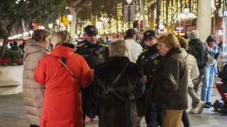 La Guàrdia Urbana patrullen per un carrer de Barcelona il·luminat amb motius nadalencs.