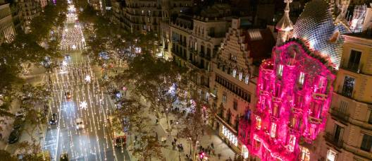 Vista aèria del passeig de Gràcia amb els llums de Nadal decorant la via i la Casa Batlló il·luminada de color fúcsia 