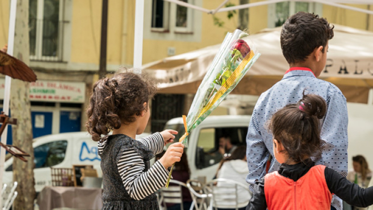Una nena, acompanyada d'una altra nena i un nen, passeja amb una rosa a la mà 