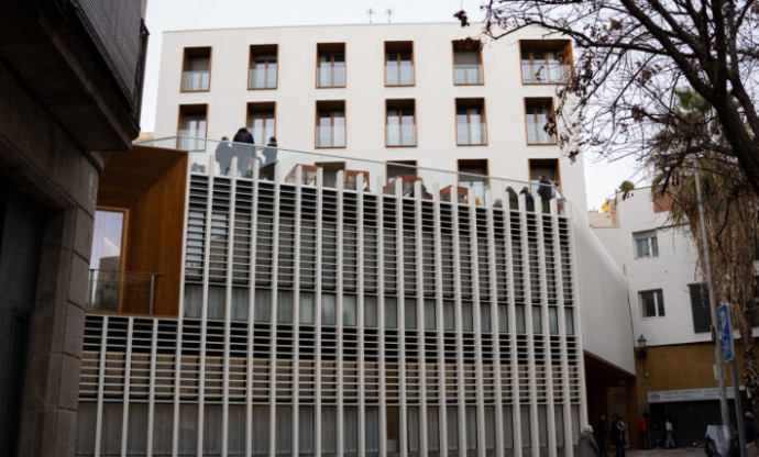 Vista exterior de la façana de lames del casal, amb persones a la terrassa superior