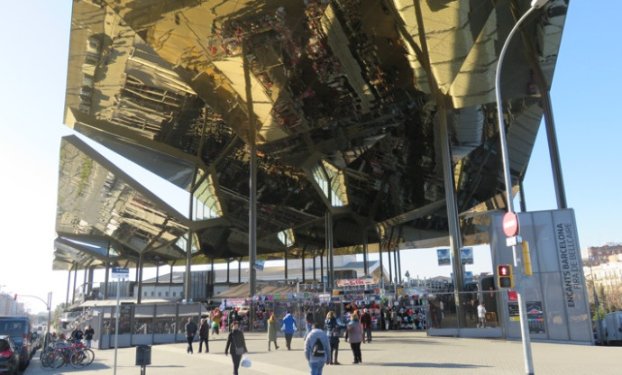 Gente paseando por el mercado de los Encants, con los reflejos de los puestos en la cubierta.