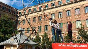 Imatge d’un entorn urbà on un grup de persones construeix una estructura a escala humana utilitzant tubs