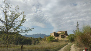Image of a rural landscape with a large farmhouse in the distance.