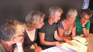 Imagen de 5 personas reunidas mirando un papel muy detenidamente.