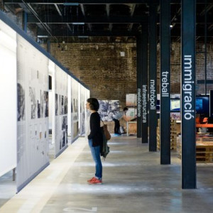 Interior de l’edifici industrial amb una exposició i persones passejant-hi