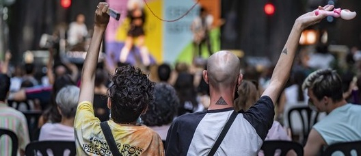 Foto: Laura Guerrero Dos nois asseguts però ballant amb la música durant el sopar d'estiu del Centre LGTBI