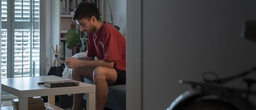 Un joven en el comedor de su casa mira el móvil