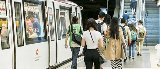 Estació de metro amb el tren aturat i persones a l’andana
