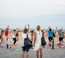 Two women watching a group of people doing yoga at the beach