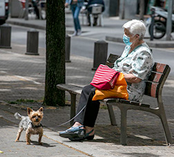 A woman with a dog sitting on a bench in Via Julia