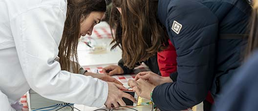Joves científiques connectant uns cables a un mòbil per a fer un experiment