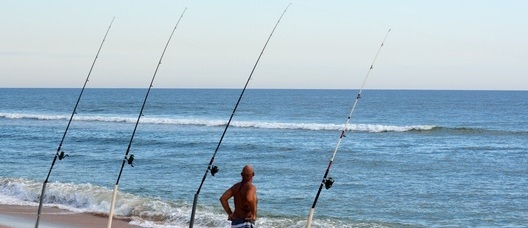 Un hombre pesca en la playa