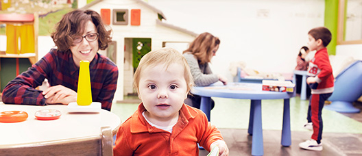 Mother watching how her son plays with a book 
