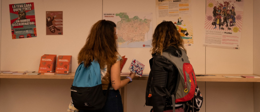 Noies llegint un díptic en un punt d'informació juvenil