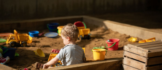 Un niño juega en el arenero del patio