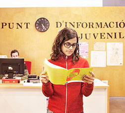 Noia llegint un díptic en un punt d'informació juvenil