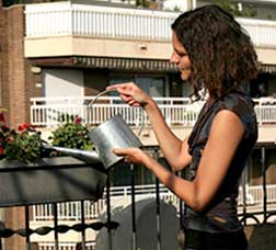 Una dona rega unes plantes a la terrassa d'un pis