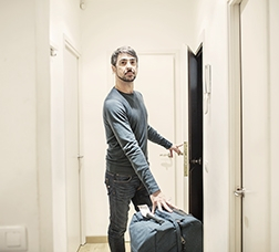 Hombre dentro de un piso con una maleta