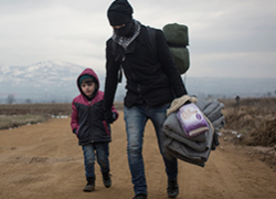 Un home i un nen refugiats caminant per un camí de sorra