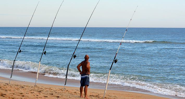 Un home pesca a la platja 